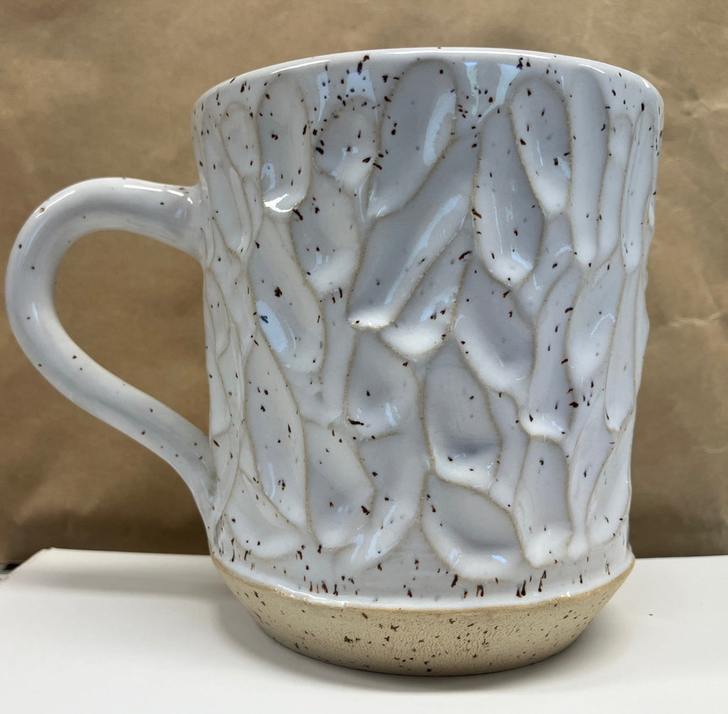 Ceramic mug with textured design on a beige background